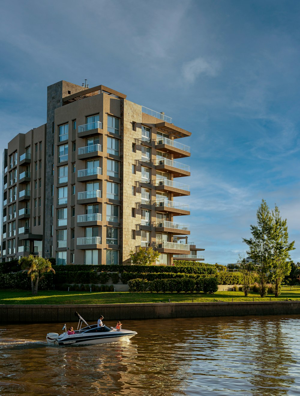 a boat traveling down a river next to a tall building