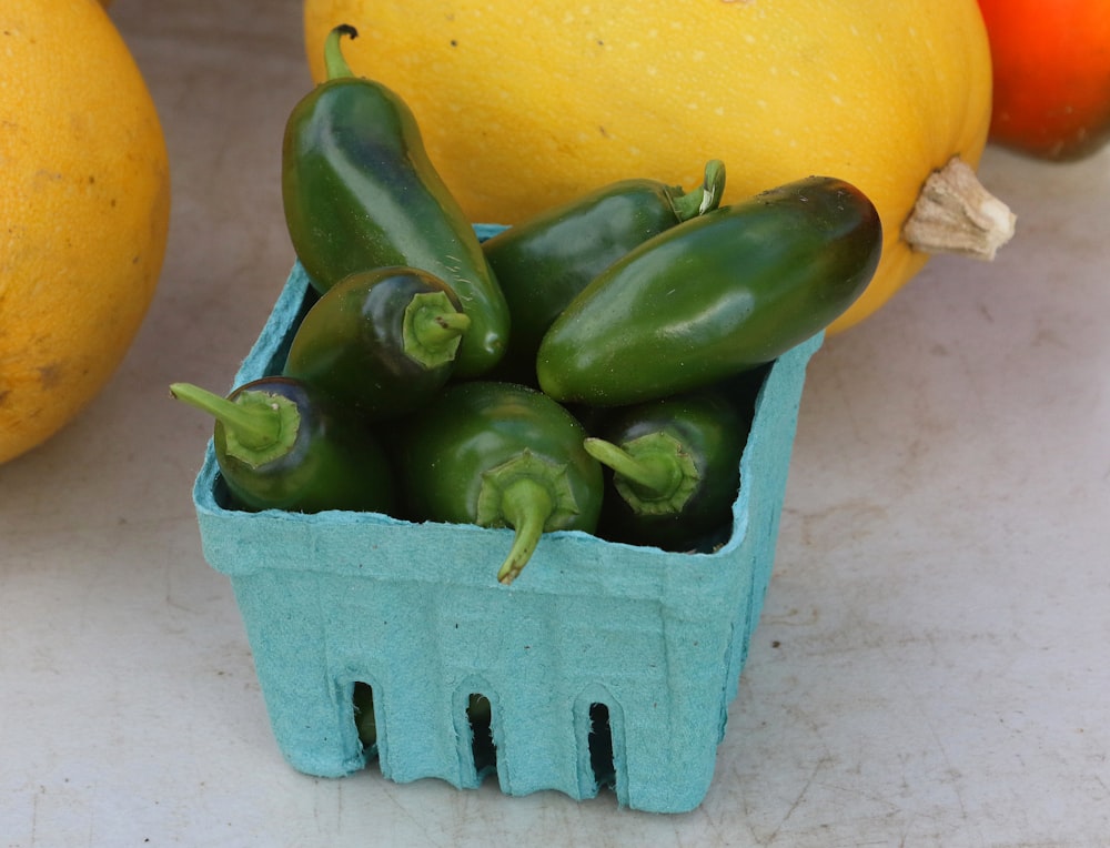 a blue container filled with green peppers next to lemons