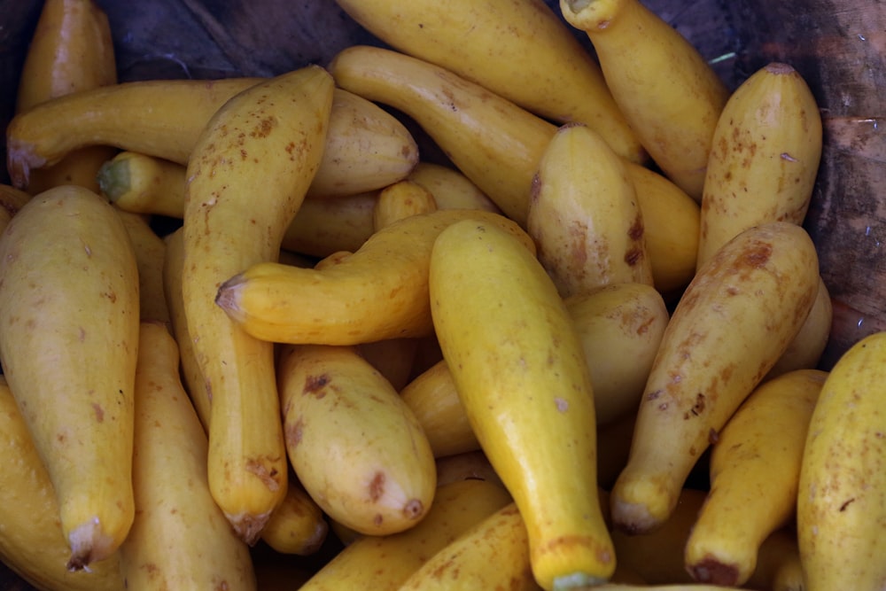 a pile of yellow squash sitting on top of a wooden table