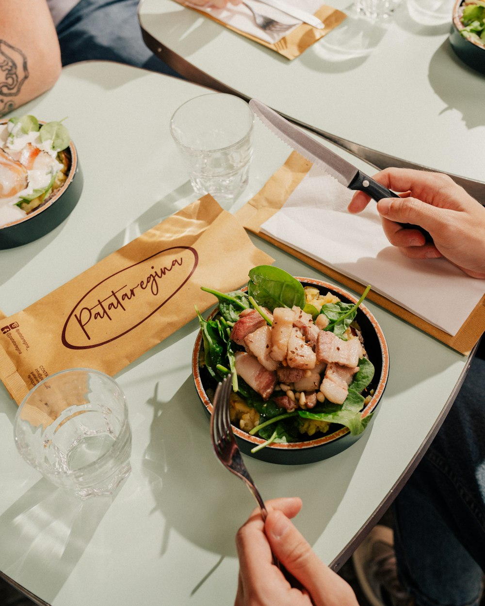 a person cutting into a salad with a knife and fork