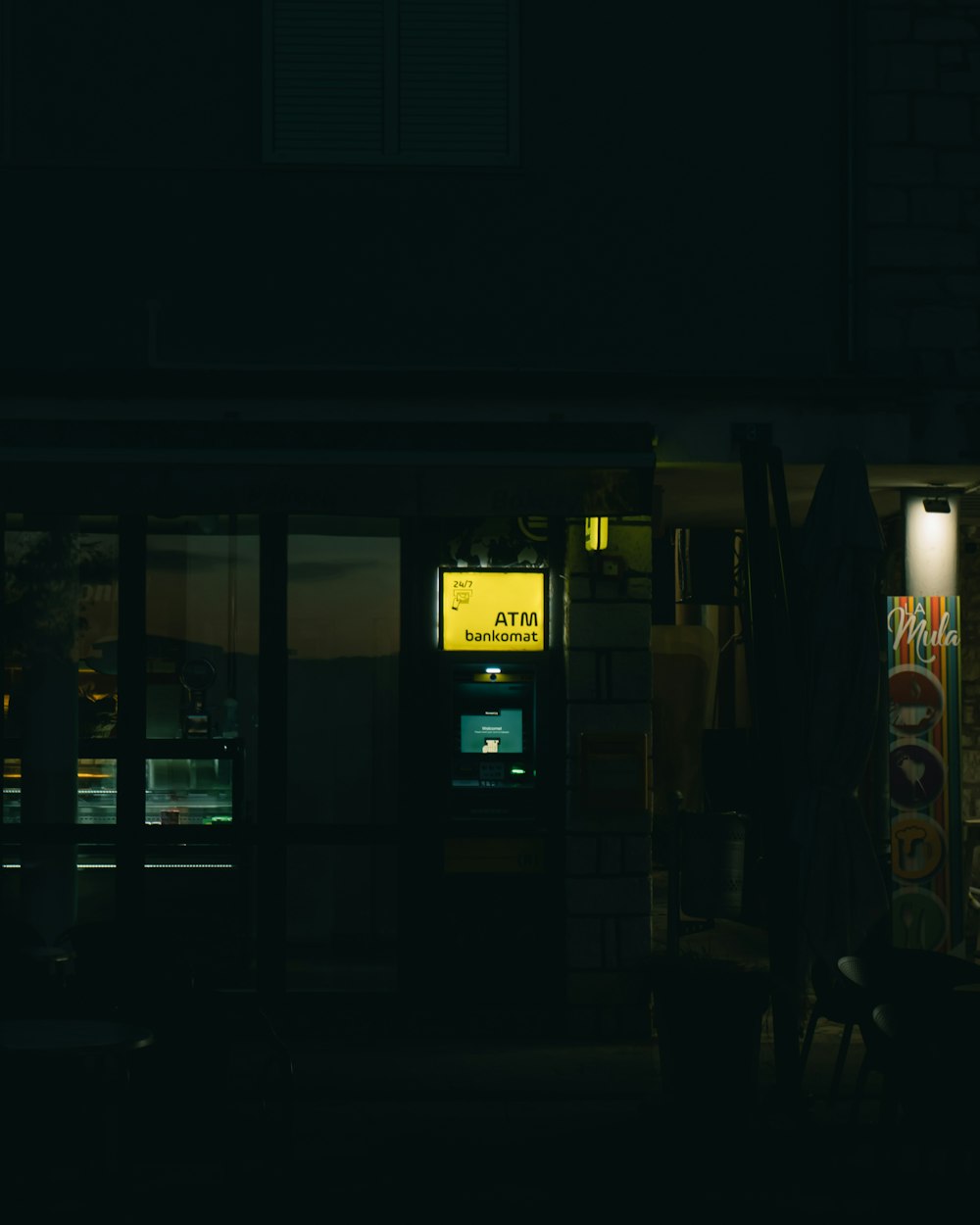 a store front at night with a lit up atm