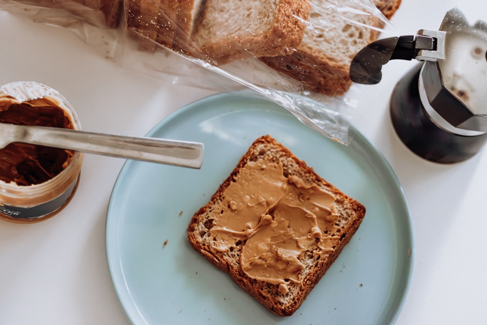 a blue plate topped with a piece of bread and peanut butter