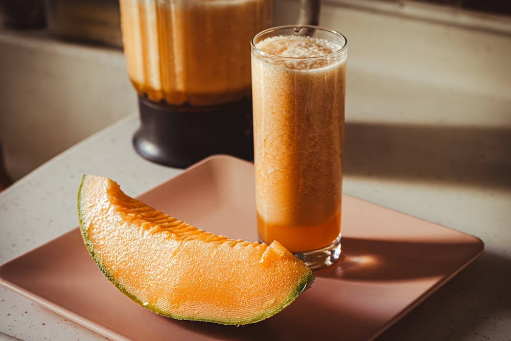 a glass of orange juice next to a sliced melon