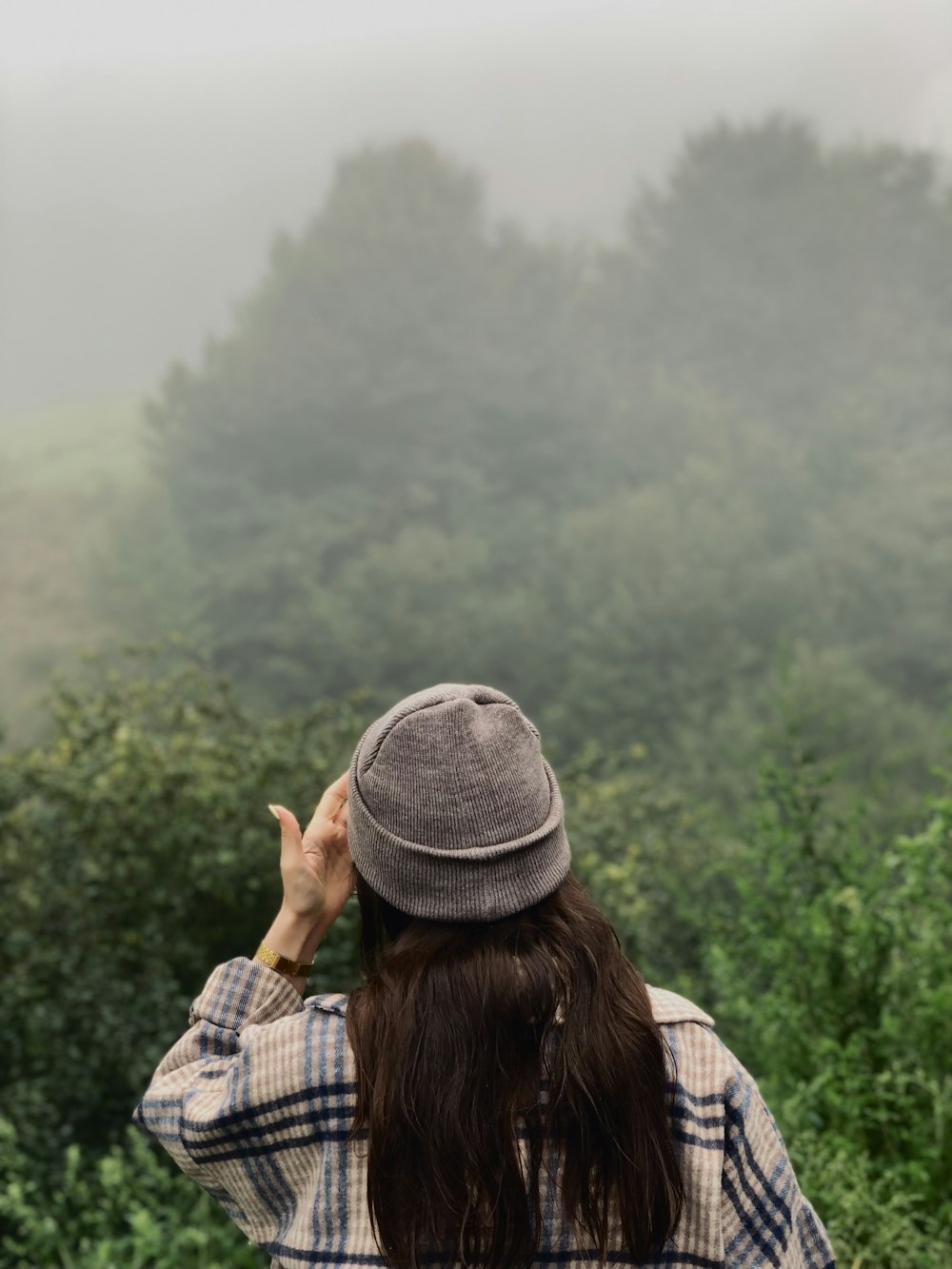 una donna in piedi di fronte a una foresta in una giornata nebbiosa