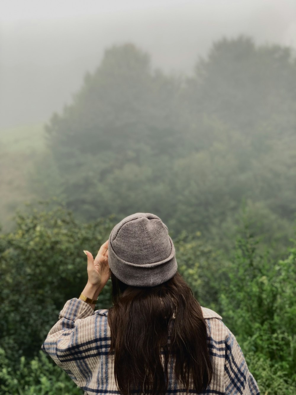 a woman standing in front of a forest on a foggy day