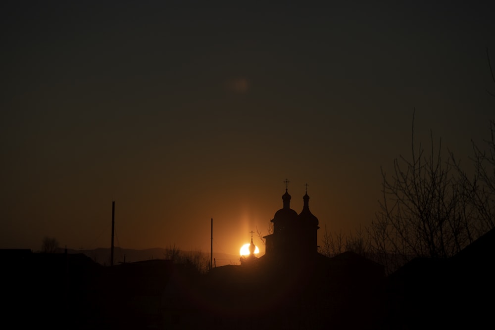 the sun is setting behind a church tower