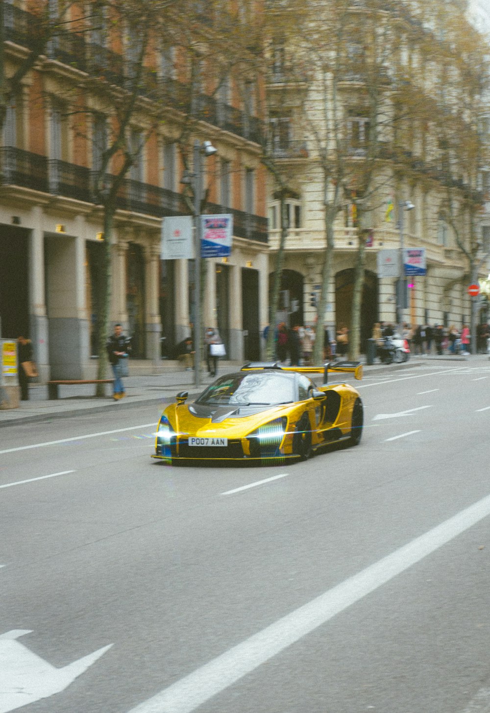 a yellow sports car driving down a city street