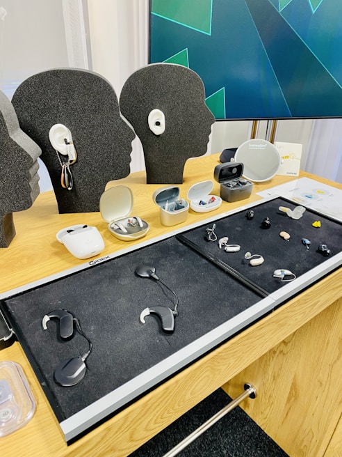 Close-up of various modern hearing aids displayed on a wooden table