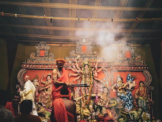 A serene image of a pandit performing a traditional pooja with saffron decorations in the background.