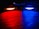 Two video game controllers are placed side by side on a wooden surface in a dark environment, emitting vibrant lights from their light bars—one glowing red and the other blue. The colors reflect off the surface, creating a striking contrast between the red and blue hues.