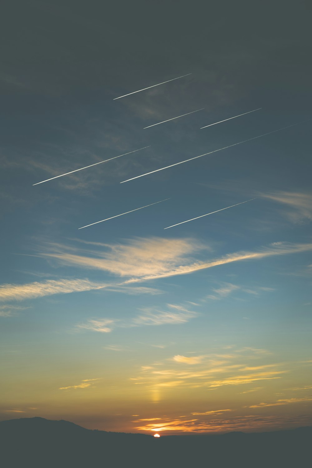 a sunset with contrails in the sky