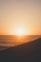 Solo traveler admiring a stunning sunset over the ocean, thanks to Carleone Neres