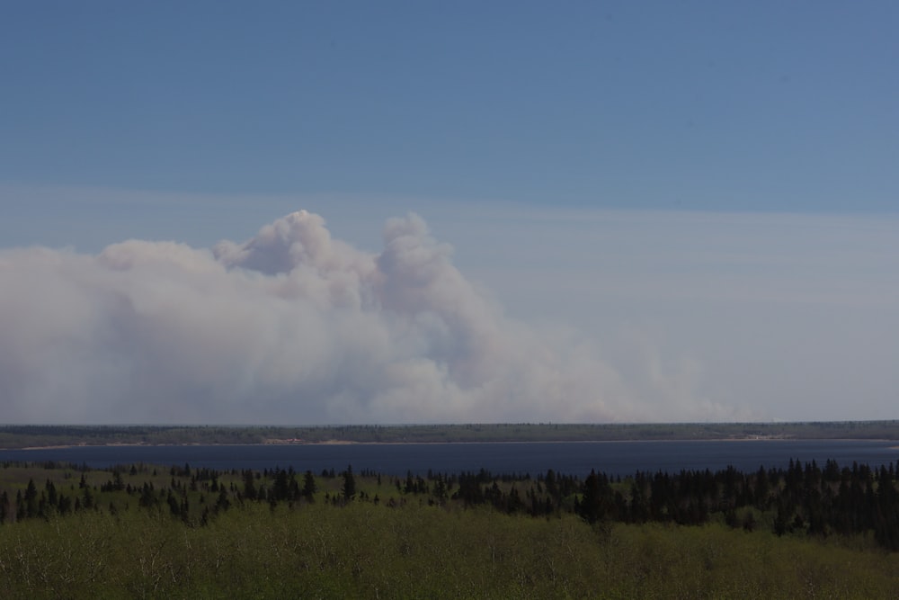 a large plume of smoke rising from a large body of water