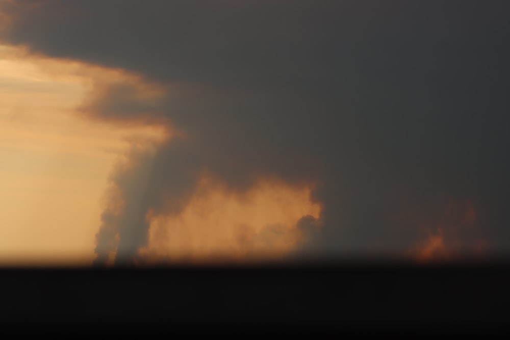 a very large cloud in the sky with the sun behind it