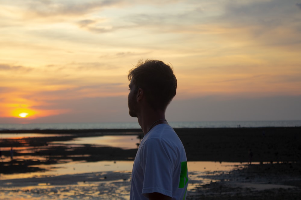 a man standing on top of a beach next to the ocean