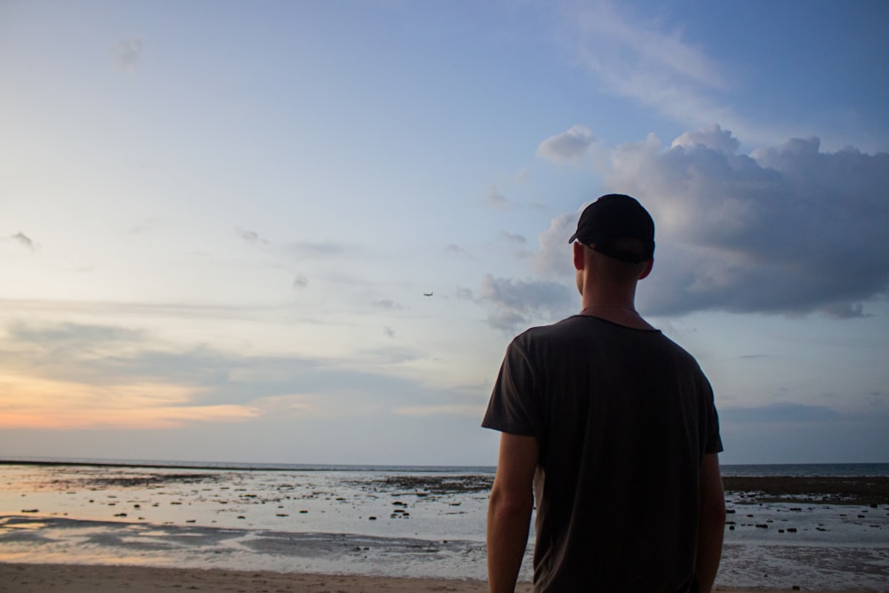 a man standing on top of a beach next to the ocean