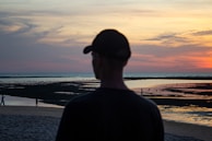 a man standing on top of a beach next to the ocean