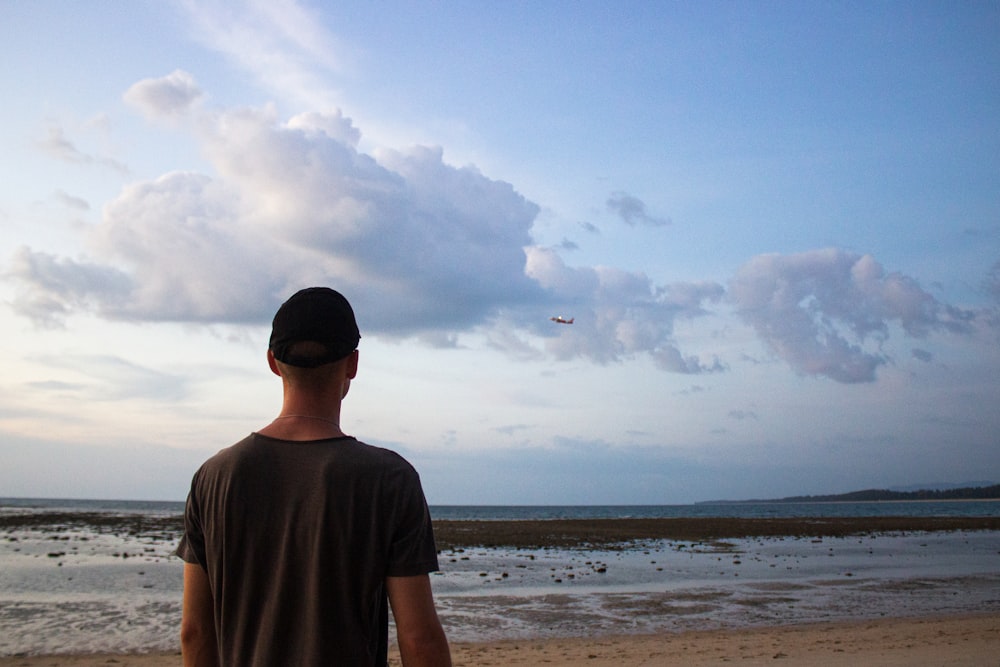 a man standing on top of a sandy beach next to the ocean