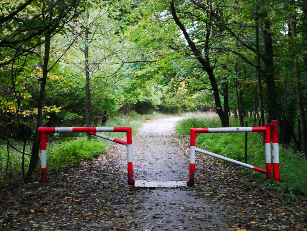 a red and white gate on a dirt road