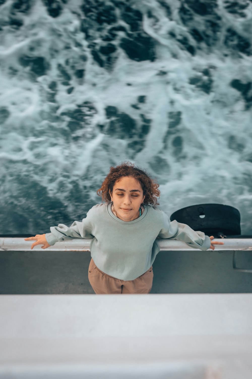 a woman standing on a boat in front of a body of water