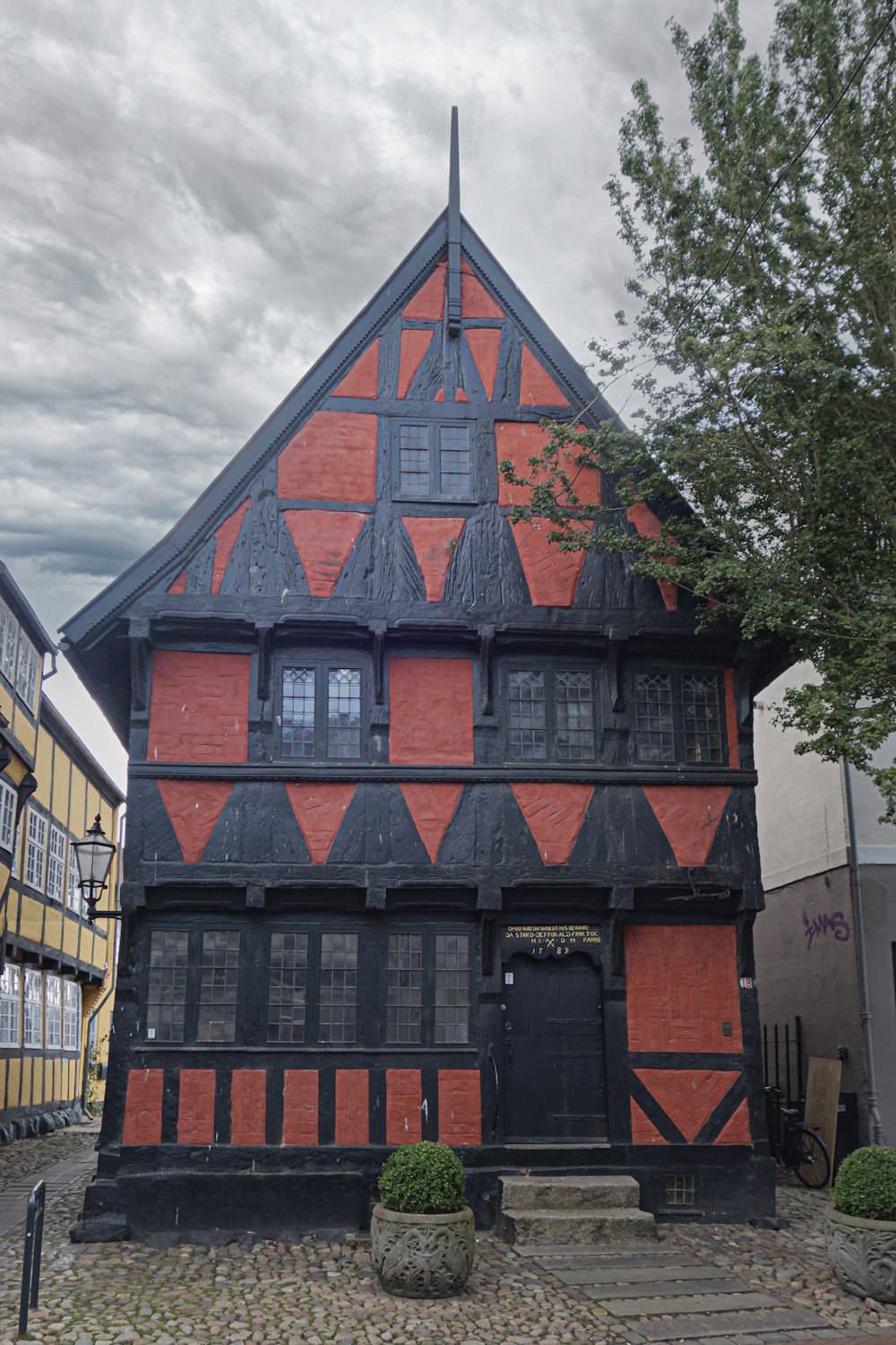 a red and black building sitting next to a tree