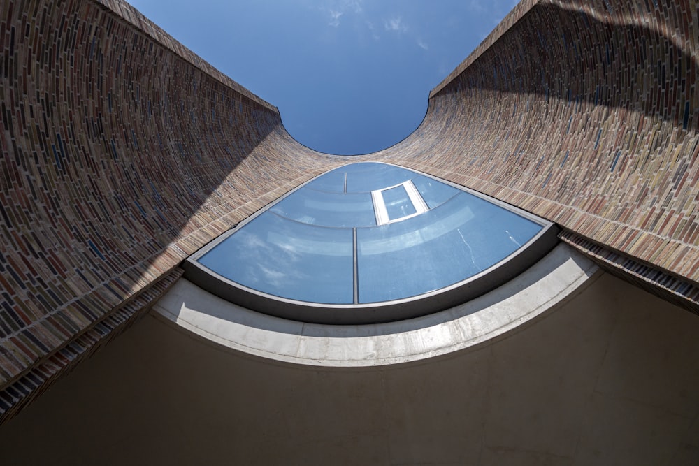 looking up at a curved building with a sky background