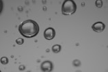 Macro shot of water droplets sliding off a treated lens surface.