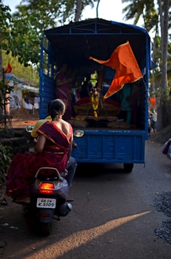 a woman sitting on a scooter in front of a blue truck
