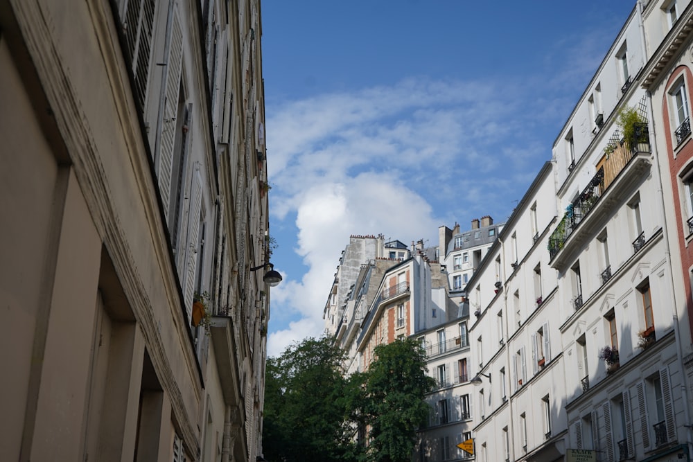 a city street lined with tall buildings under a cloudy blue sky