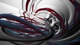 A digital abstract art piece featuring swirling, intertwined structures resembling twisted cables or ropes with a smooth, metallic appearance. The scene conveys a sense of motion and complexity through its intricate patterns and reflective surfaces, blending shades of red, blue, and silver.