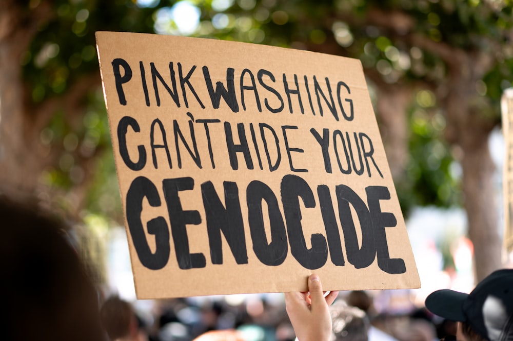 a person holding a sign that says pinkwashing can't hide your gen