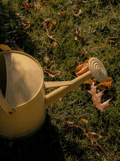 a yellow watering can sitting in the grass