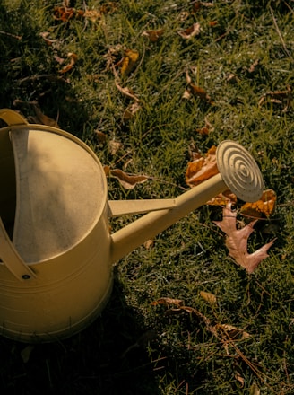 a yellow watering can sitting in the grass