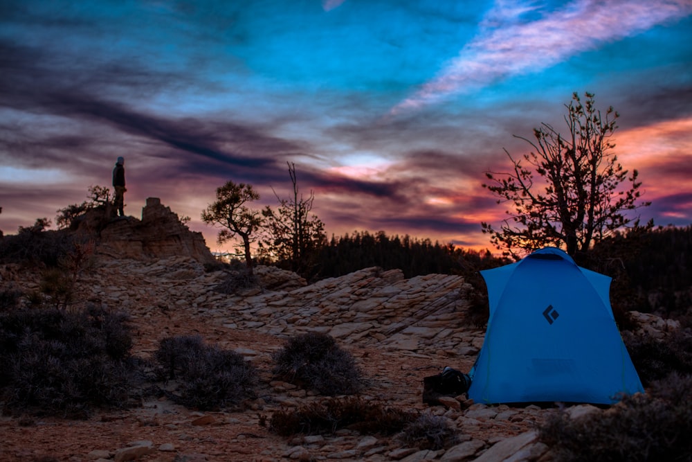 a blue tent sitting on top of a rocky hillside