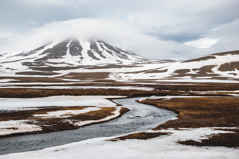 a snowy mountain with a stream running through it