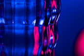 Close-up of a glassmorphism panel with floating pink shapes and subtle glow effects on a dark background.