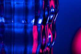 Close-up of a glassmorphism panel with floating pink shapes and subtle glow effects on a dark background.