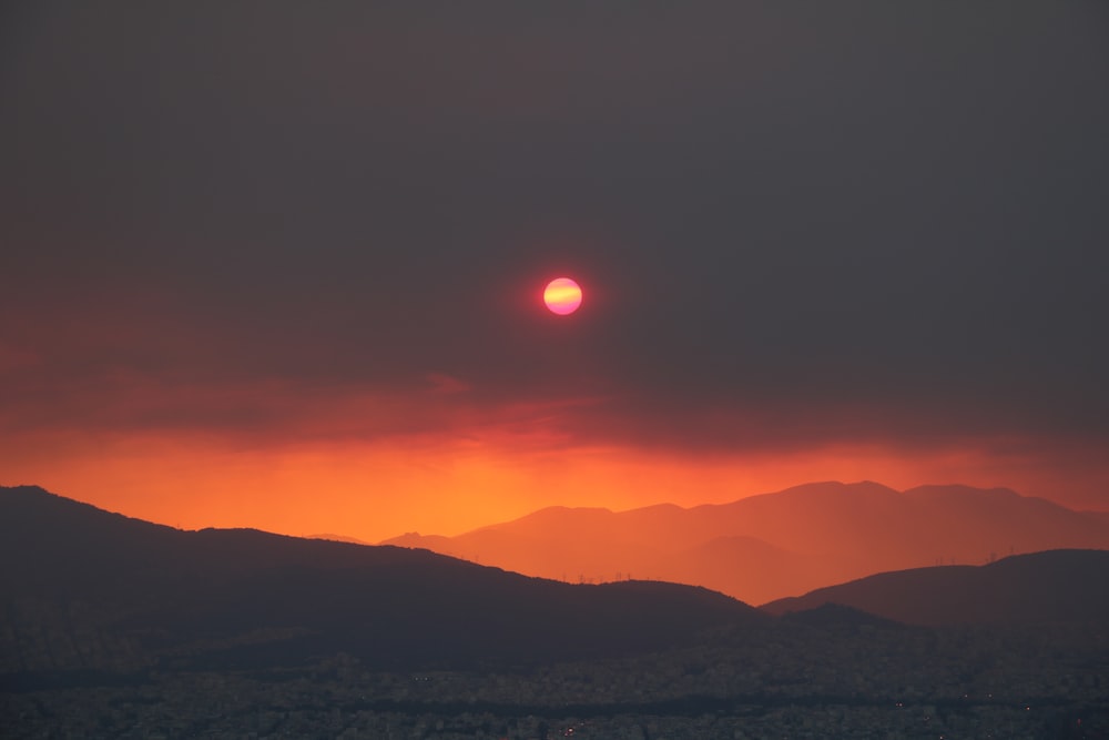 the sun is setting over a mountain range