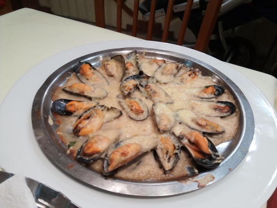 A vibrant display of mussels served with various colorful sauces.