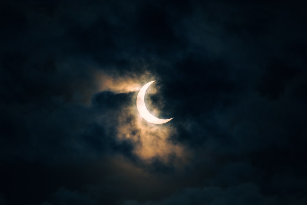 the moon is partially obscured by a cloudy sky