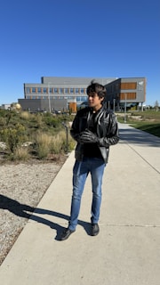 A satisfied customer wearing a sleek black leather jacket standing outside the rlb clothing ltd workshop in Hailsham.