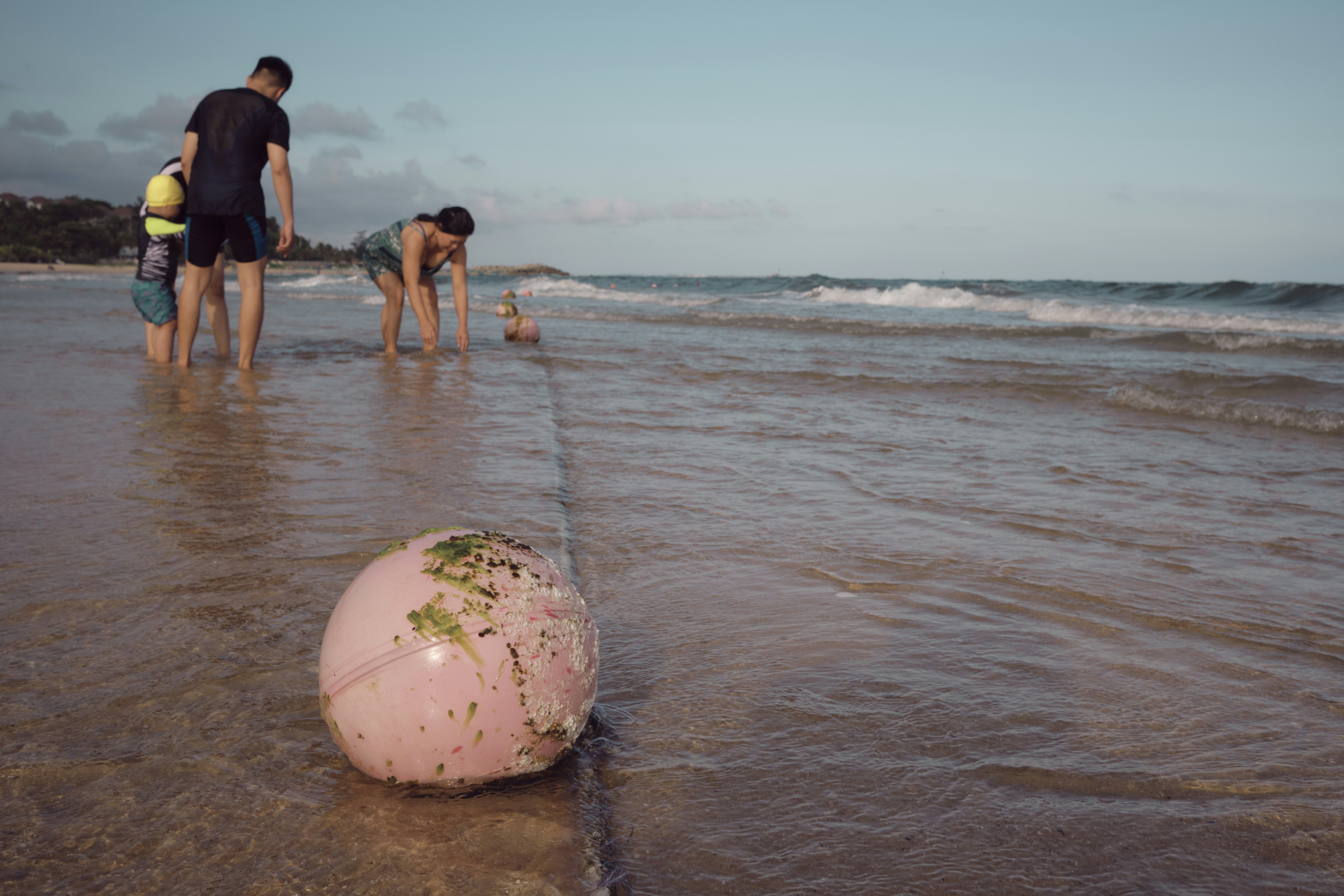 um grupo de pessoas em cima de uma praia ao lado de um corpo d'água