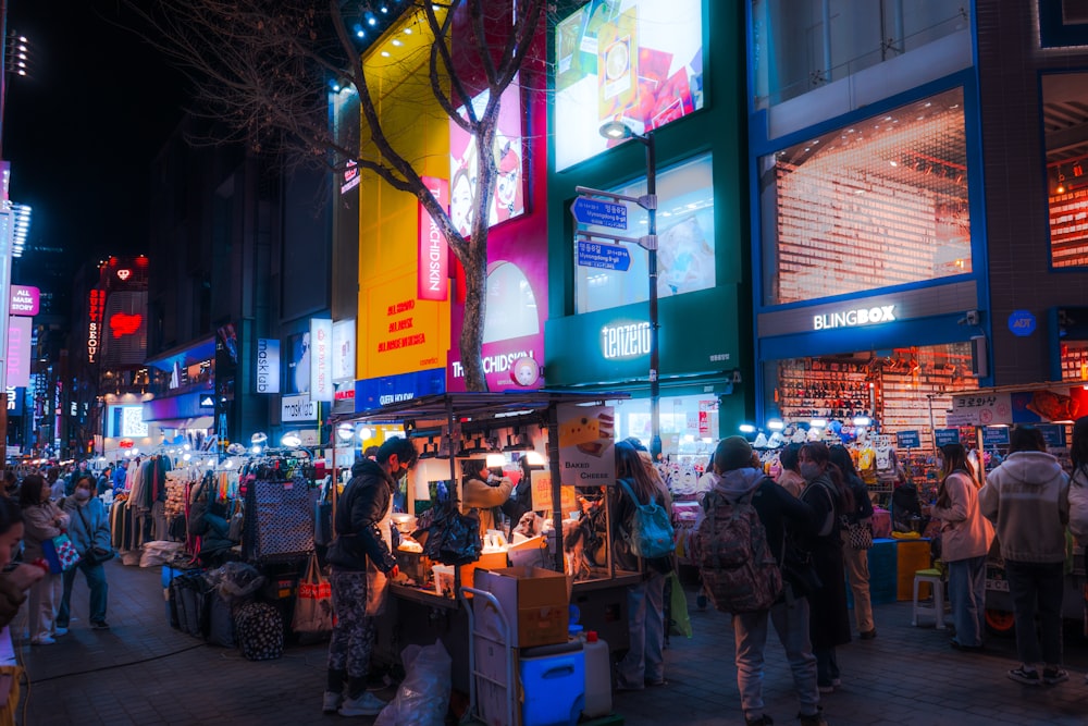 a crowd of people standing around a store at night