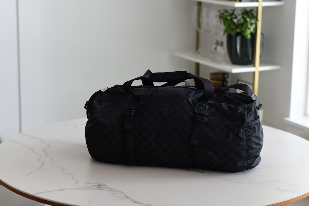 a black duffel bag sitting on top of a white table
