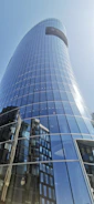 Close-up of a sleek glass facade reflecting the Sudanese skyline under a clear blue sky.
