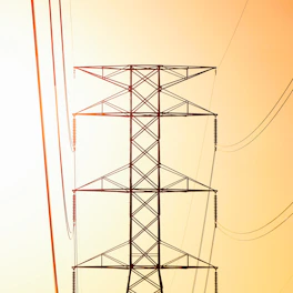 a high voltage power line against an orange sky