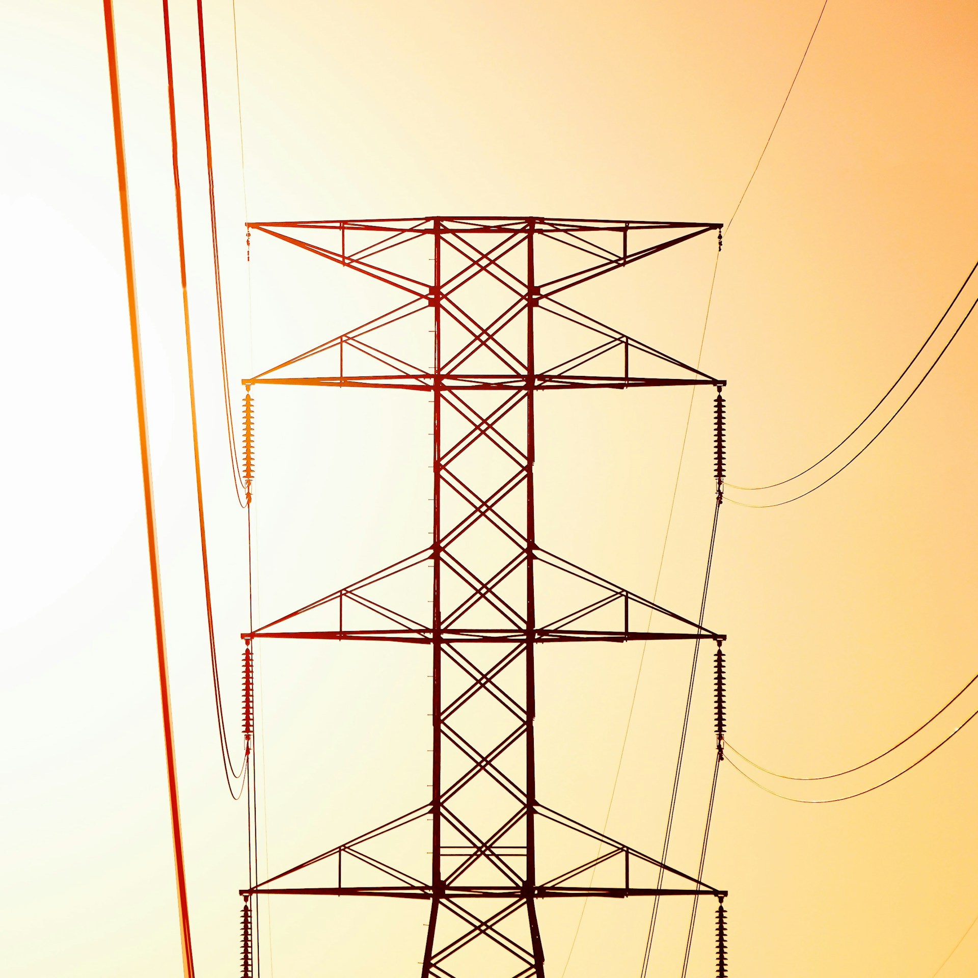 a high voltage power line against an orange sky