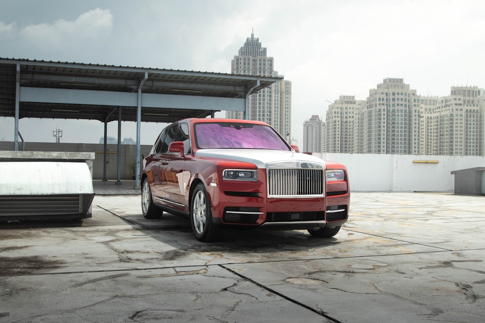 a red rolls royce parked in front of a building