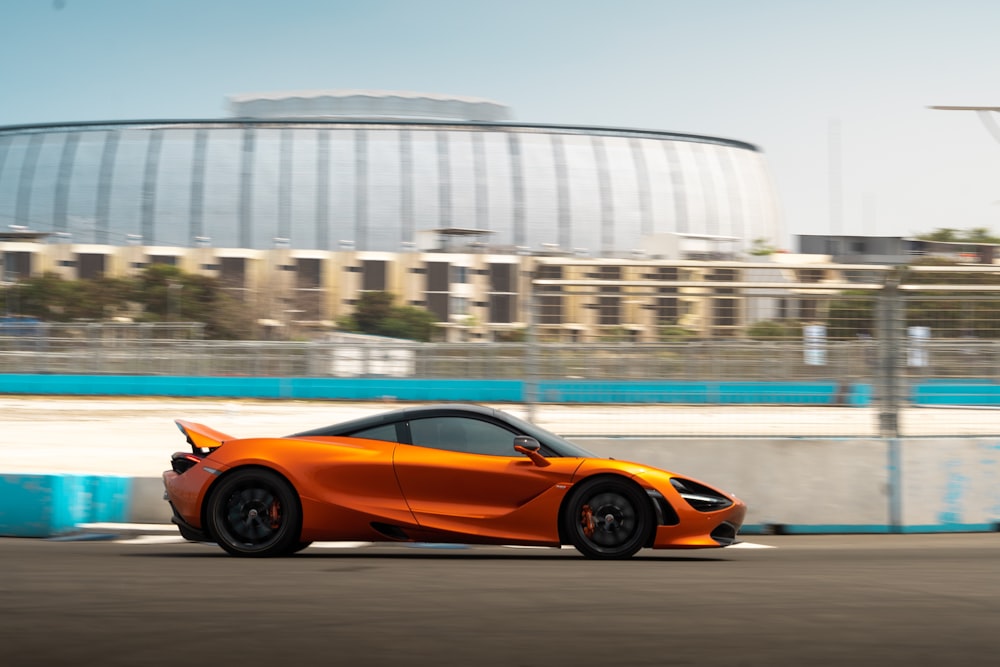 an orange sports car driving down a race track