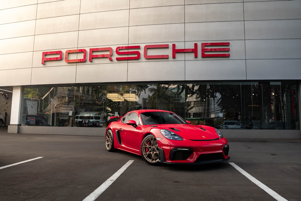 Um carro esportivo vermelho estacionado em frente a uma concessionária Porsche